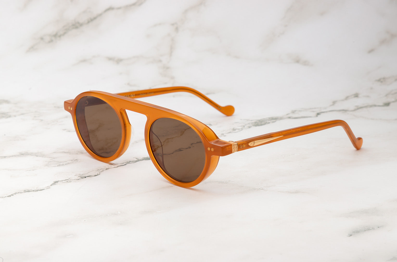 A pair of orange round sunglasses for men by Peter Frank.