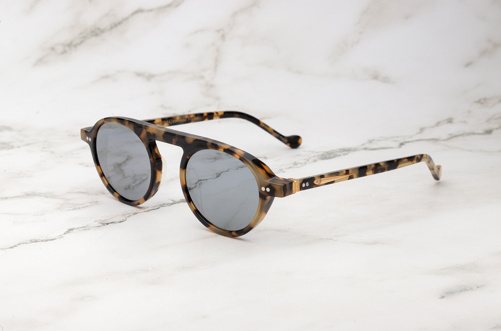 Small round sunglasses by Peter Frank, offering a subtle look.