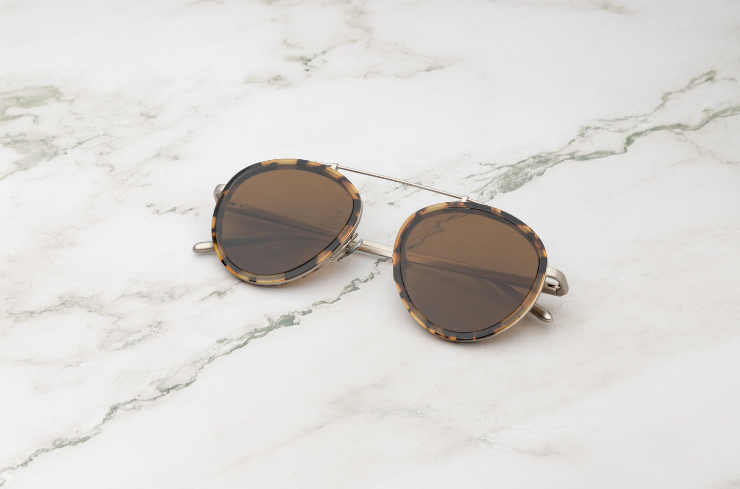 A man wearing the Sasha Davidov, a pair of men's military aviator sunglasses in brown.