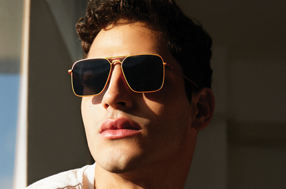 Model wearing Hector Gonzales aviator sunglasses by Kopajos with gold frame and dark polarized lenses.