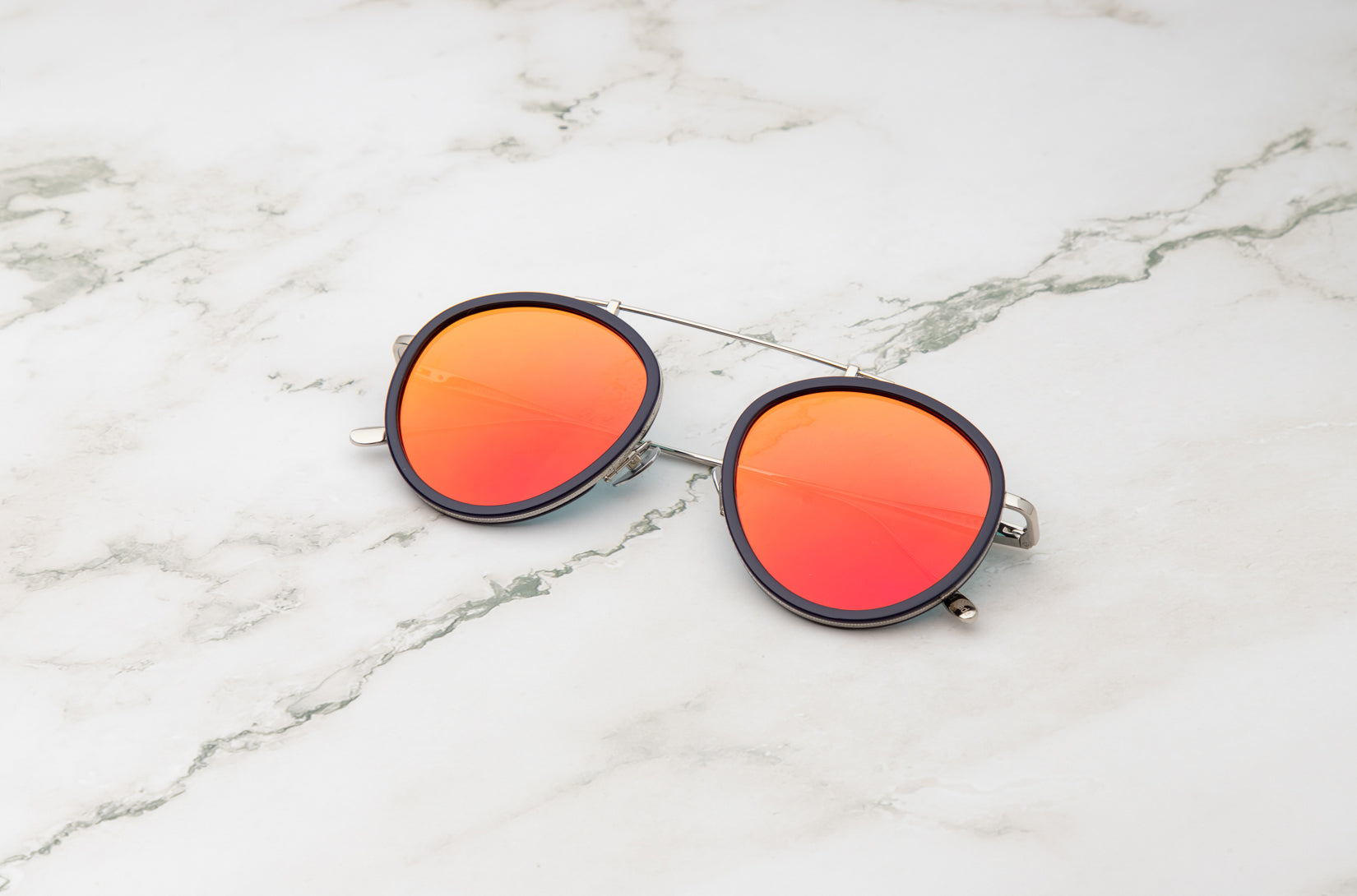 The warm tones of the Sasha Davidov red aviator sunglasses against a sunset.